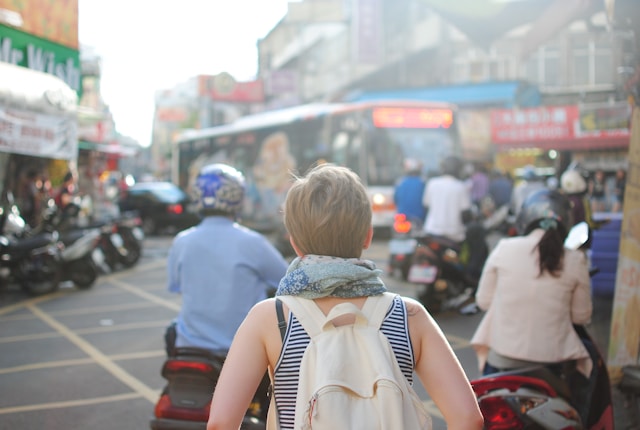 A young woman walking alone in a foreign city street at dawn or dusk, exuding serenity amidst cultural surroundings and scenic architecture.