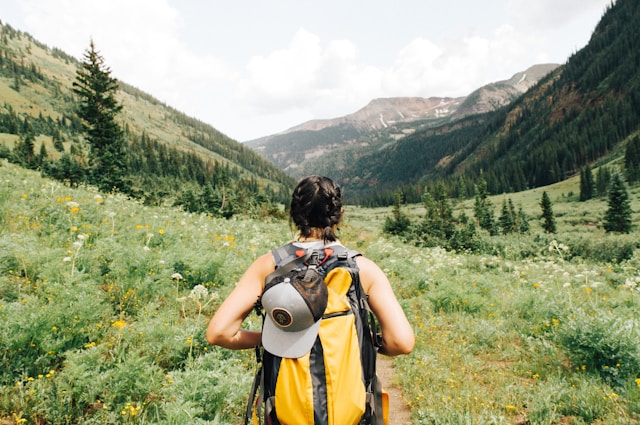 Young woman hiking at sunset in a breathtaking natural landscape, exuding adventure and freedom, conveying excitement and thrill-seeking spirit.