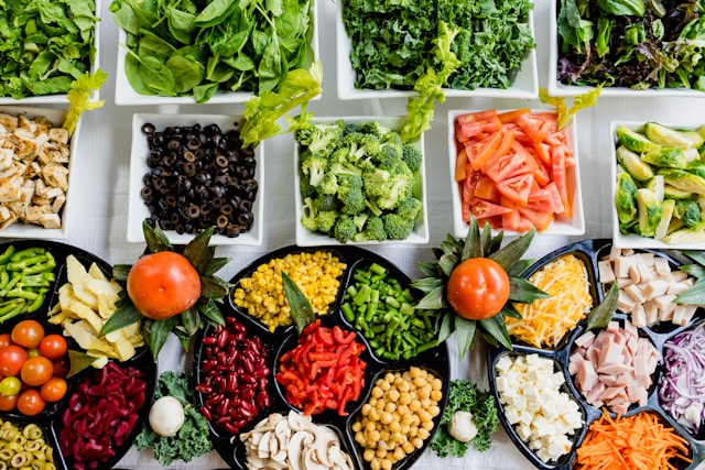 Colorful arrangement of diverse whole foods including fruits, vegetables, and greens emphasizing healthy eating options and nutritious diet.