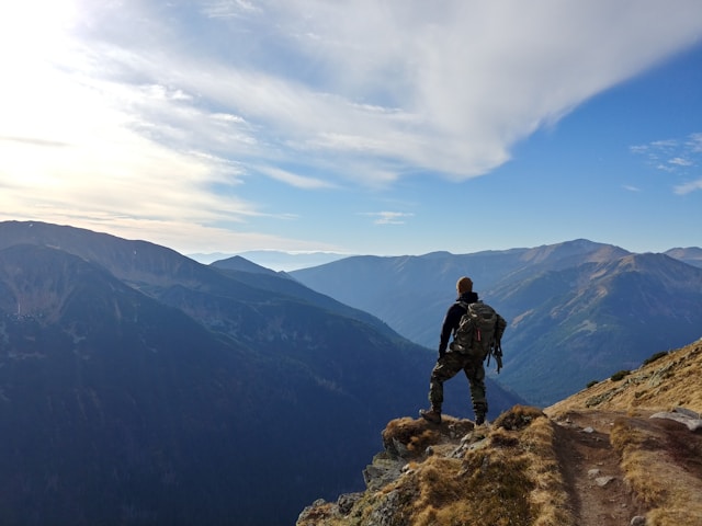 A thrill-seeking traveler hiking amidst breathtaking natural landscapes, rugged mountains, serene lakes, and vibrant cityscapes in outdoor adventure travel settings.